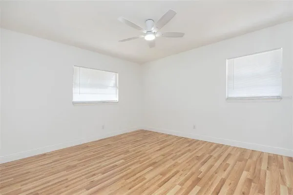 an empty room with wooden floor and windows