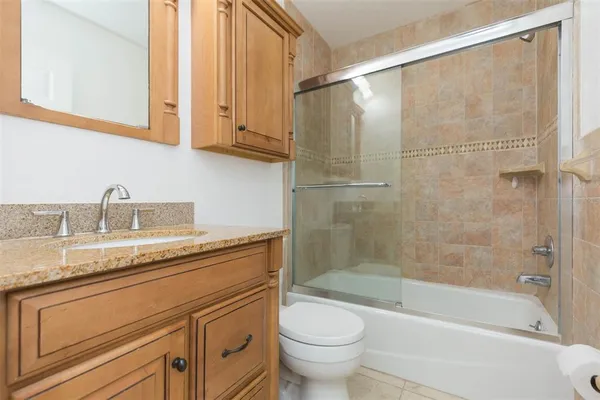 a bathroom with a granite countertop sink a toilet and bathtub