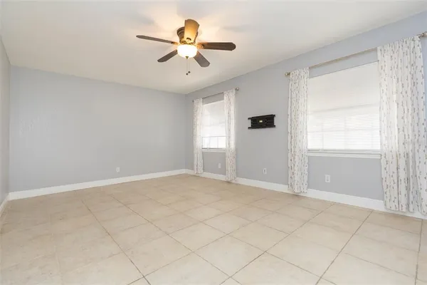 an empty room with windows and fan