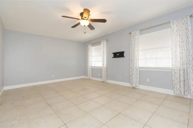 an empty room with windows and fan