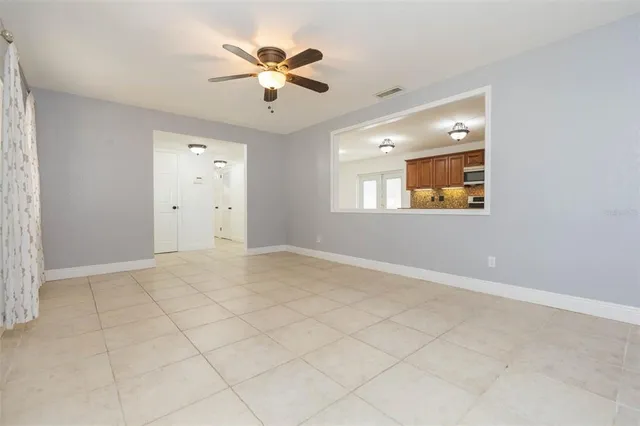 an empty room with chandelier fan and windows