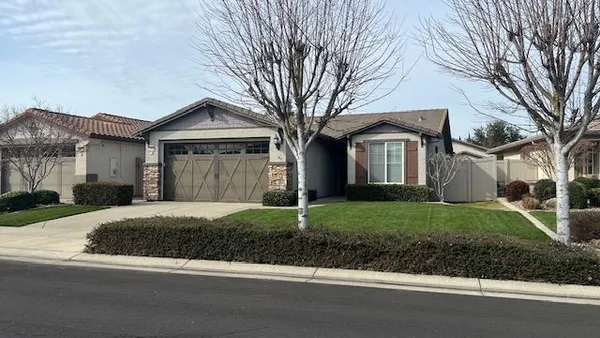 a front view of a house with a garden and trees