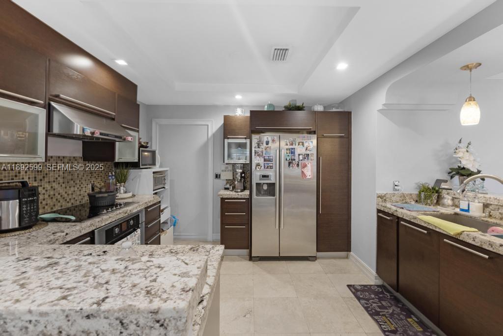 155 West 60th Street Hialeah, FL 33012 - Photo 11 of 29 a kitchen with stainless steel appliances kitchen island granite countertop a refrigerator and a stove top oven