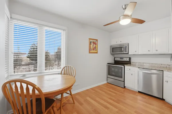 a kitchen with stainless steel appliances granite countertop a dining table chairs refrigerator and microwave