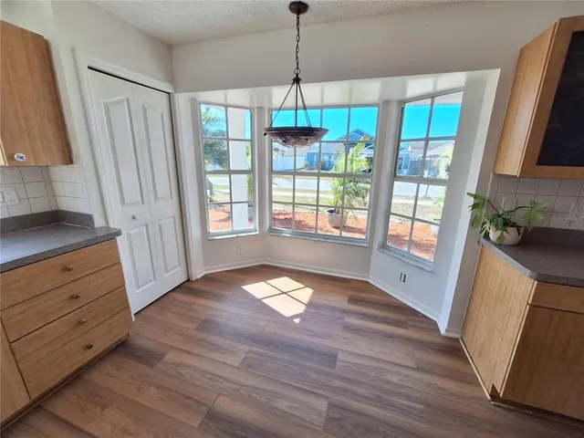 a view of an empty room with wooden floor and a ceiling fan