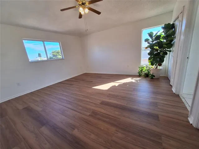a view of an empty room with a window and wooden floor