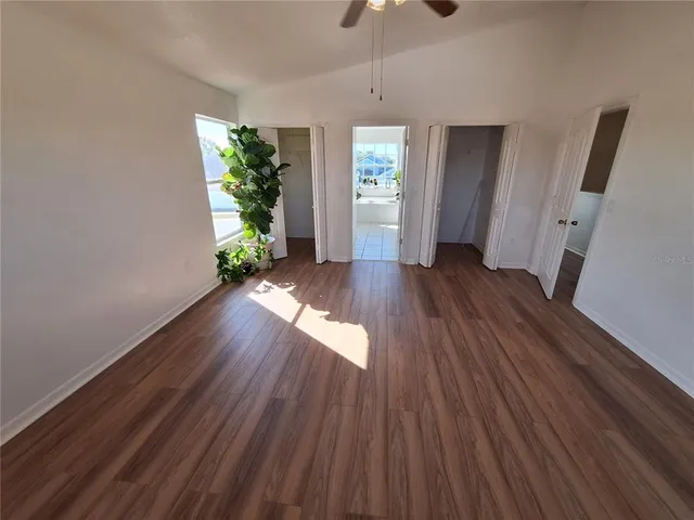 a view of an empty room with a window and wooden floor