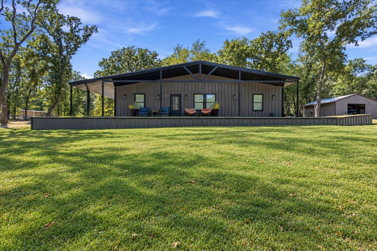 12 Hoot Loop Cartwright, OK 74731 - Photo 1 of 35 Modern barn-style residence with an expansive covered porch, dark gray exterior siding, and a standing seam metal roof
