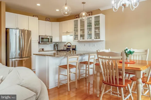 a kitchen with stainless steel appliances granite countertop a refrigerator a stove a sink dishwasher a dining table and chairs with wooden floor