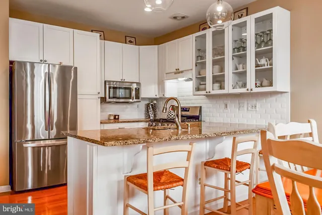a kitchen with stainless steel appliances granite countertop a refrigerator and a stove top oven