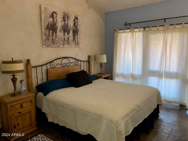 a bedroom with a bed a painting on the wall and a window