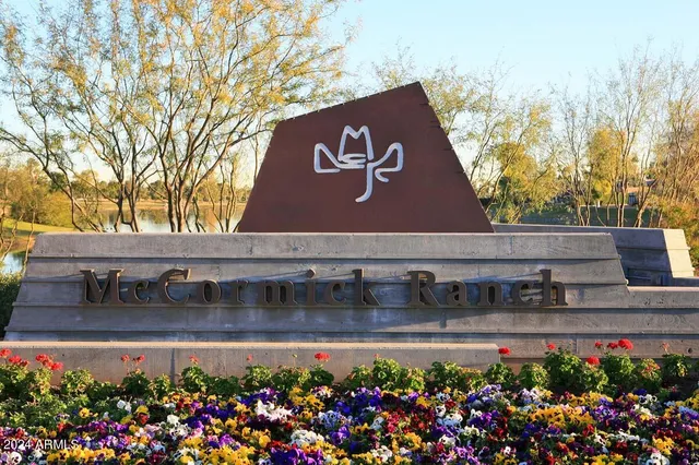 a view of a sign board with flower plants in front of main door