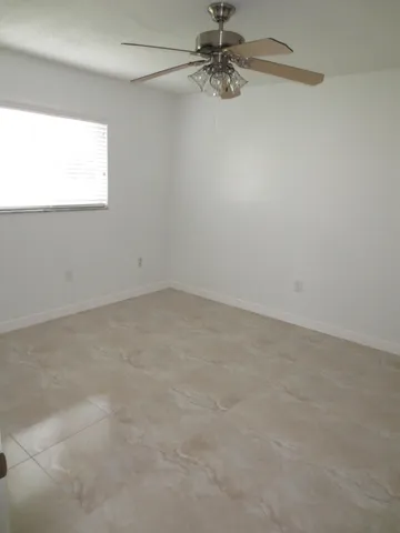an empty room with a window and a fan