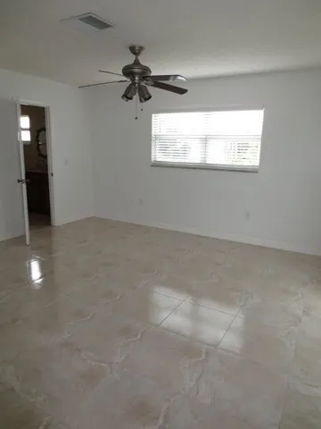 an empty room with windows and fan