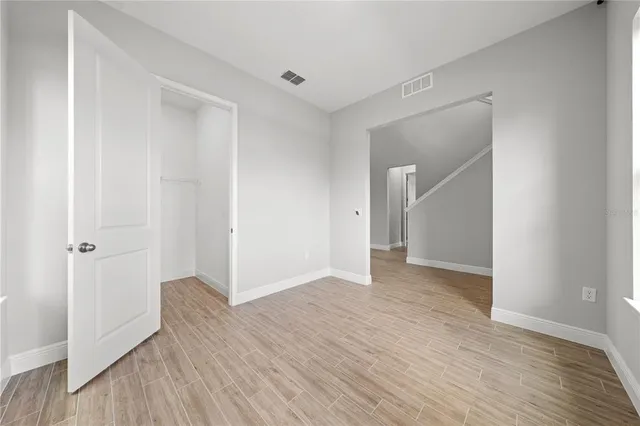 a view of a hallway with wooden floor and a bathroom