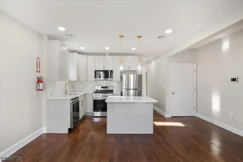 a kitchen with stainless steel appliances kitchen island wooden floors and white cabinets