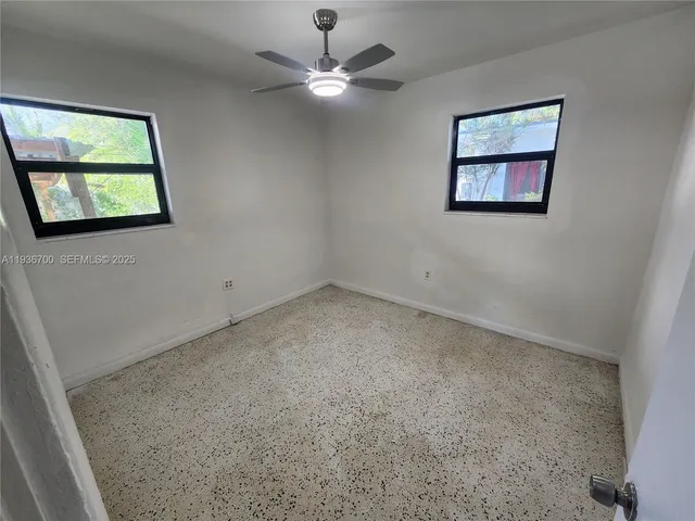 an empty room with windows and fan