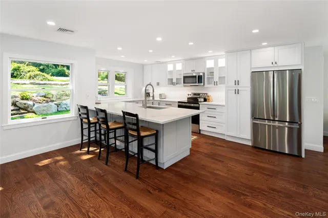 a kitchen with stainless steel appliances a dining table chairs stove refrigerator and wooden floor