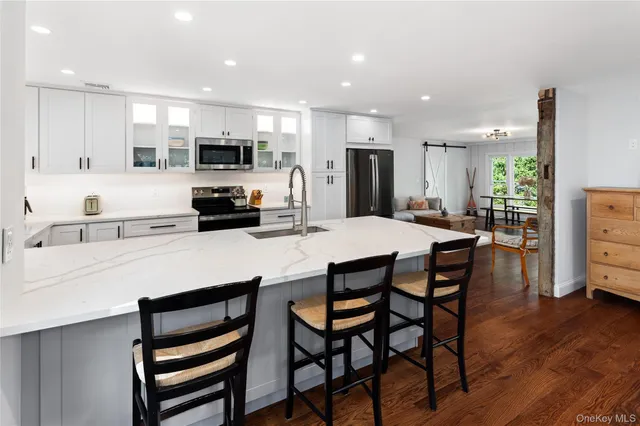 a kitchen with stainless steel appliances kitchen island granite countertop a dining table chairs and sink