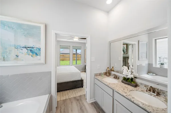 a en suite bathroom with a granite countertop tub a double vanity sink and a window