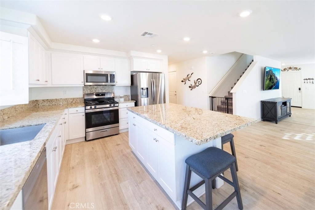 32078 Rambling Court Winchester, CA 92596 - Photo 17 of 48 a large kitchen with stainless steel appliances kitchen island granite countertop a stove a sink dishwasher and a refrigerator with wooden floor
