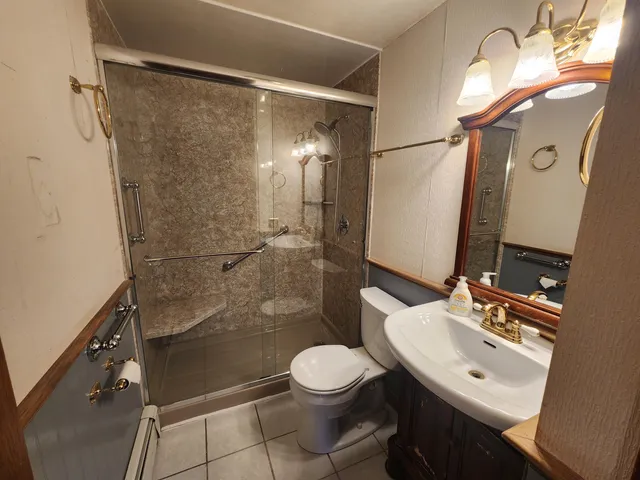 a bathroom with a sink toilet a mirror and shower