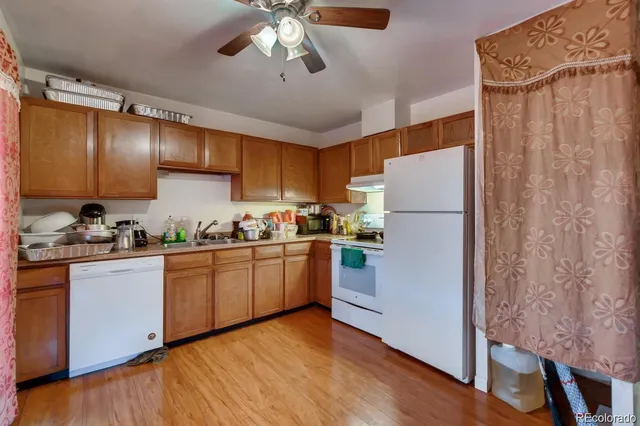 a kitchen with granite countertop a refrigerator a sink and white cabinets
