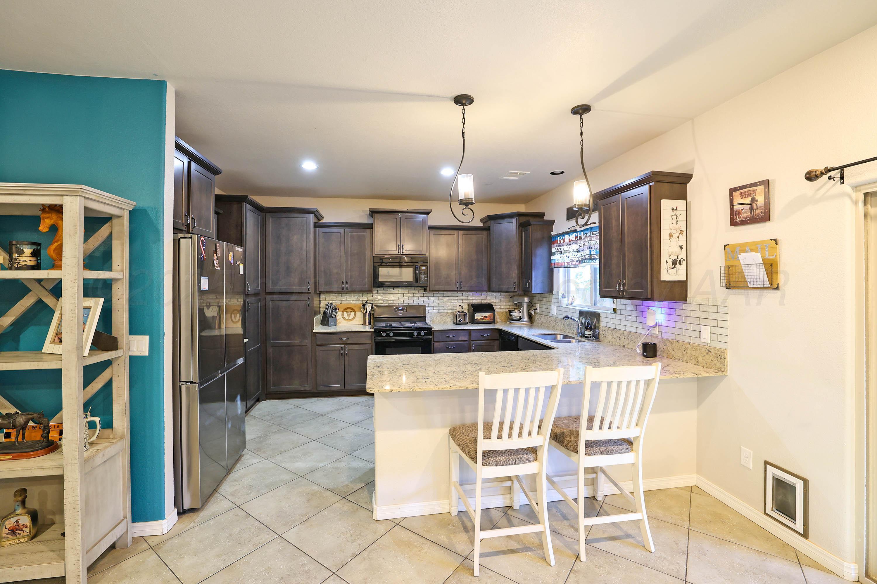 1003 Cabernet Way Amarillo, TX 79124 - Photo 13 of 36 a kitchen with stainless steel appliances granite countertop a stove a refrigerator a oven a sink with a dining table and chairs