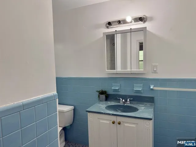 a bathroom with a granite countertop sink and a toilet