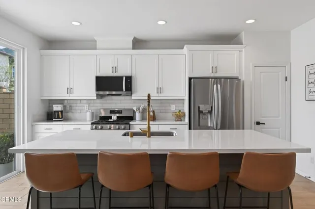a kitchen with a sink a stove a refrigerator and white cabinets