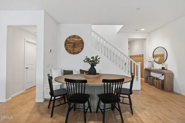 a kitchen with stainless steel appliances granite countertop a dining table chairs refrigerator and sink