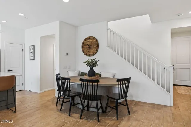 a kitchen with stainless steel appliances granite countertop a dining table chairs refrigerator and sink