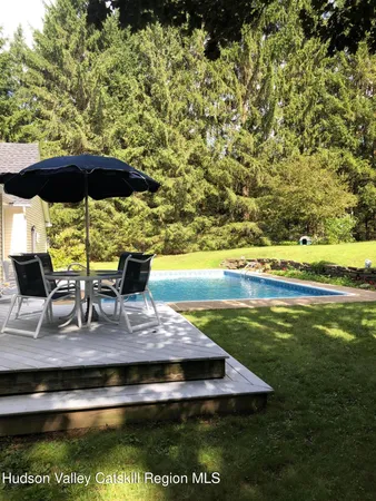 a view of a swimming pool with lawn chairs under an umbrella