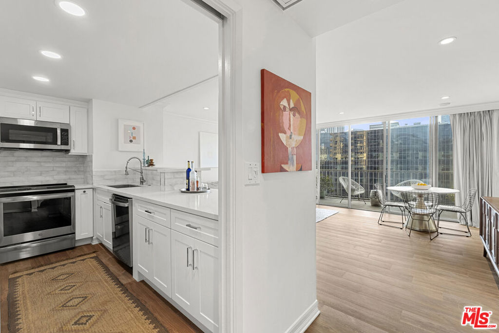 2160 Century Hill, Unit 910 Los Angeles, CA 90067 - Photo 5 of 20 a open kitchen with granite countertop a stove top oven a sink a dining table and chairs with wooden floor