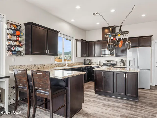 a kitchen with stainless steel appliances granite countertop a stove top oven a sink dishwasher and a refrigerator with wooden floor