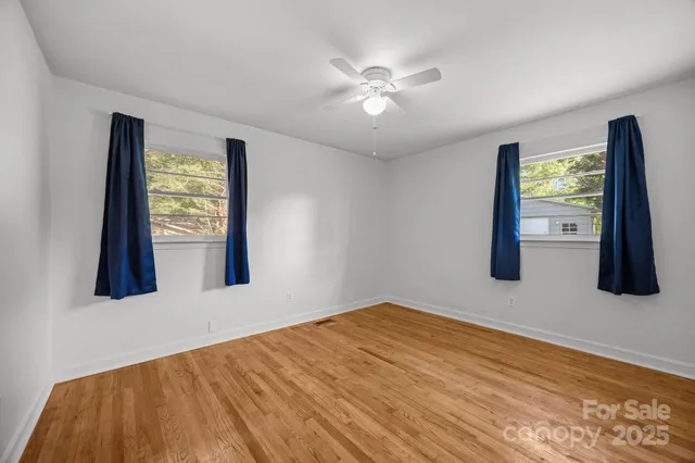 a view of an empty room with window and wooden floor