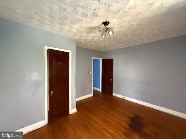 an empty room with wooden floor and chandelier fan