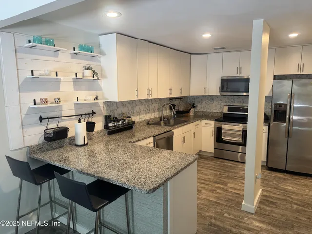 a kitchen with stainless steel appliances granite countertop a sink a stove and a refrigerator