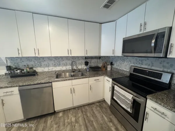 a kitchen with appliances a sink and cabinets