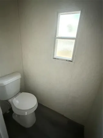 a white toilet sitting in a bathroom next to a window