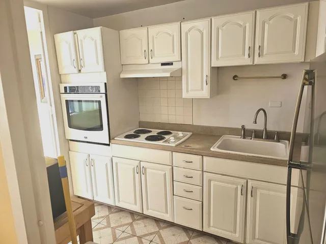 a kitchen with white cabinets and sink