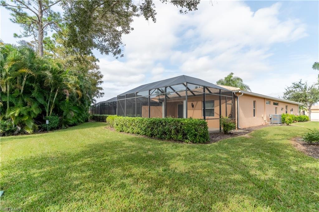 15313 Cortona Way Naples, FL 34120 - Photo 20 of 28 a view of a house with a big yard potted plants and large tree