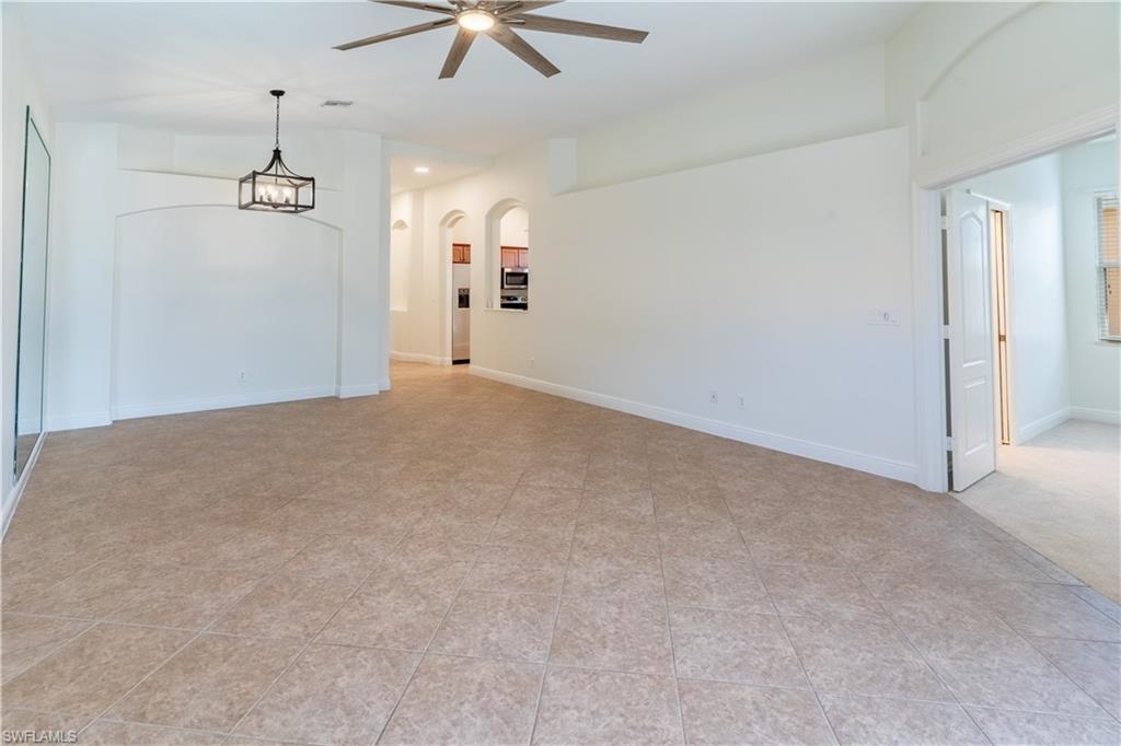15313 Cortona Way Naples, FL 34120 - Photo 9 of 28 en empty room with windows and ceiling fan