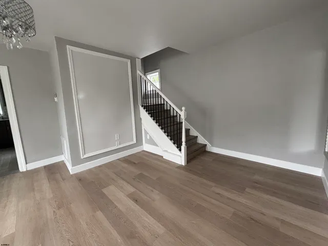 a view of an empty room with wooden floor and stairs