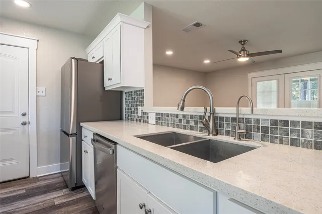 an empty room with wooden floor fan and windows