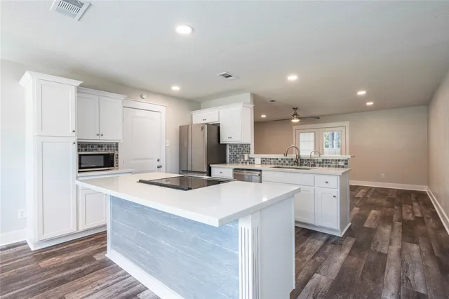 a kitchen with granite countertop a stove a sink and a microwave