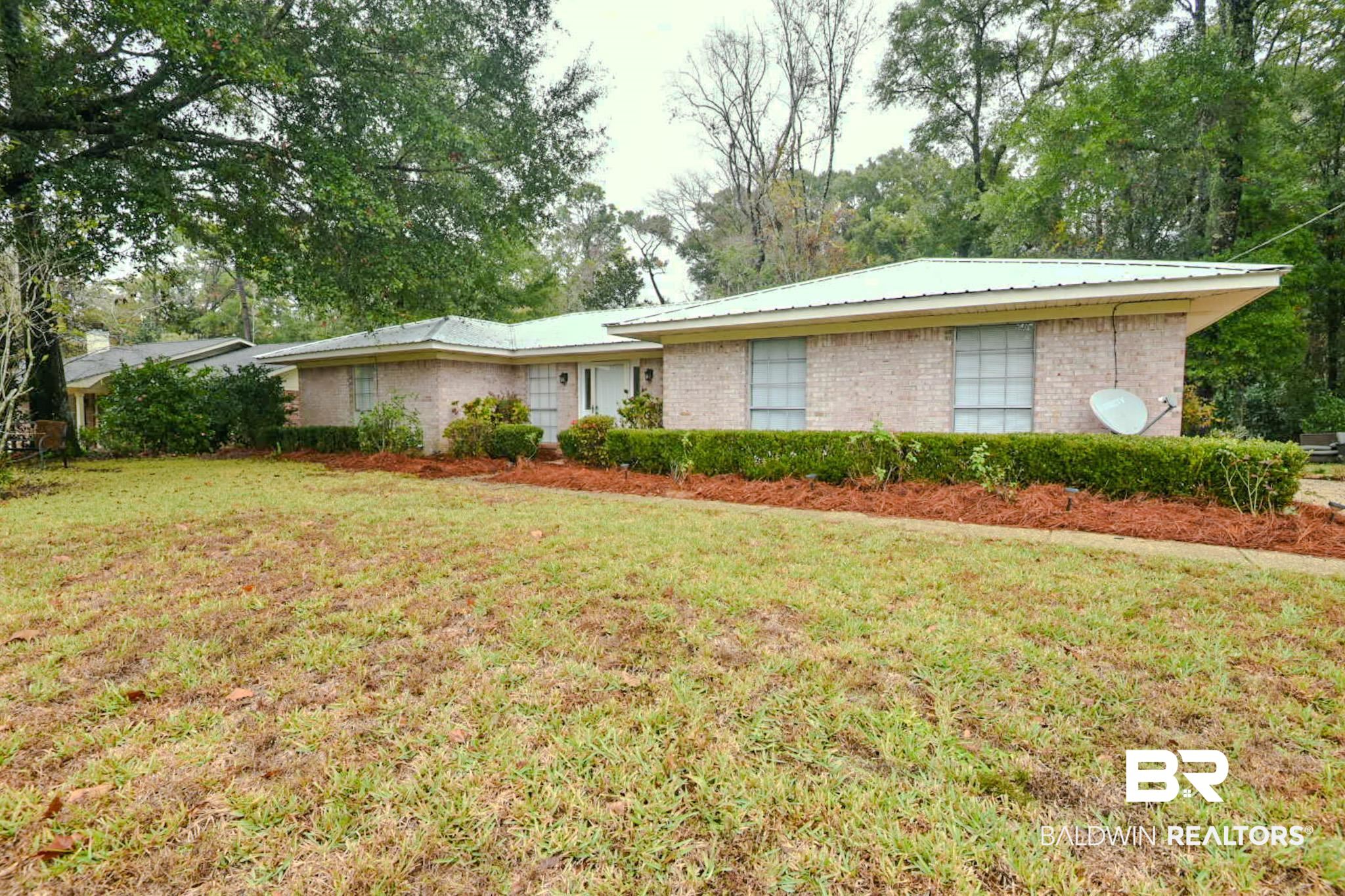 90 Paddock Drive Fairhope, AL 36532 - Photo 3 of 23 Single story home with brick siding, a front yard, view of wooded area, and a metal roof