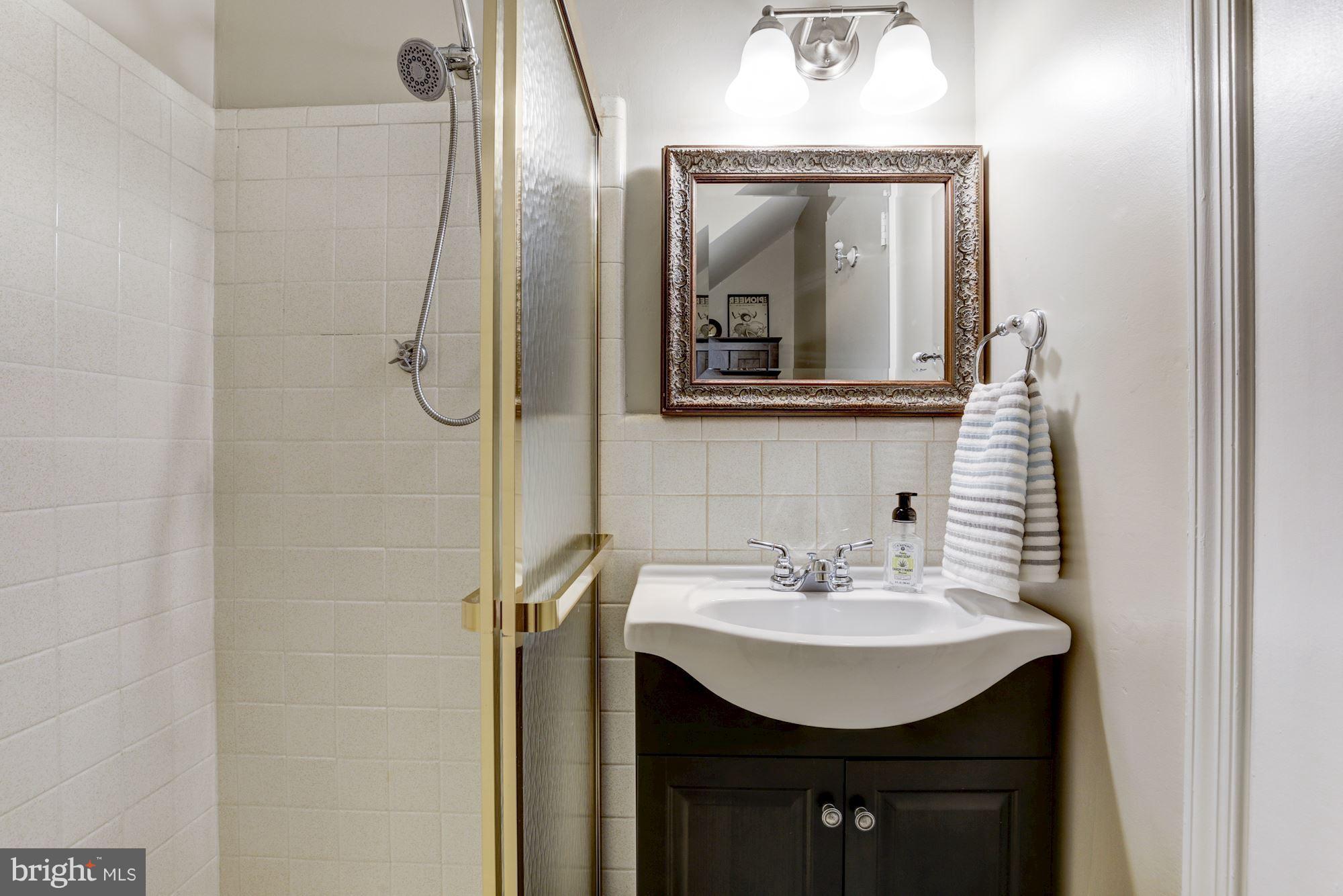 4801 Little Falls Road Arlington, VA 22207 - Photo 20 of 28 a bathroom with a sink a mirror a vanity and shower