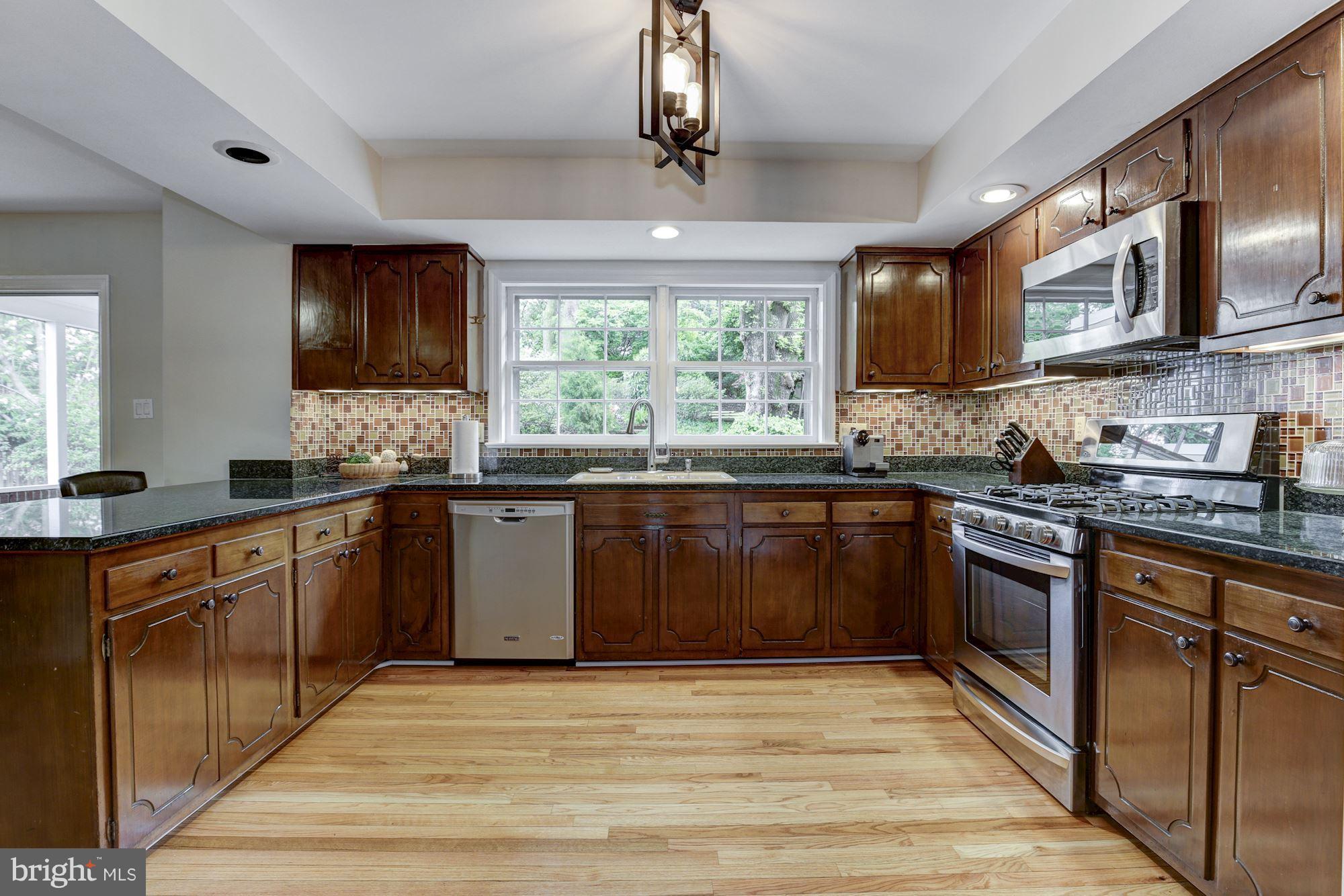4801 Little Falls Road Arlington, VA 22207 - Photo 8 of 28 a kitchen with stainless steel appliances granite countertop a stove a sink dishwasher and a microwave oven with large wooden cabinets