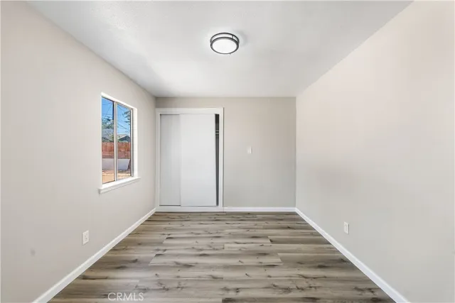 a view of an empty room with wooden floor and window